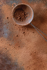 Different kind of cocoa powder as background with vintage sieve over dark old metal surface