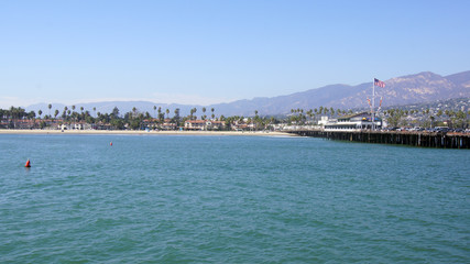 Fototapeta na wymiar SANTA BARBARA, CALIFORNIA, USA - OCT 8th, 2014: View of palm trees on the shore and mountains from Stearn's Wharf