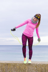 Woman training outdoor with jump rope on cold day