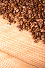 Roasted coffee beans spread over on wooden table.
