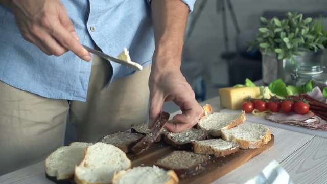 Male hands spreading butter on bread in kitchen
