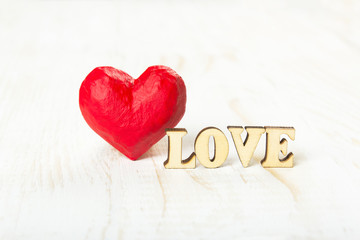 Red heart and the word love made of wooden letters on a white background