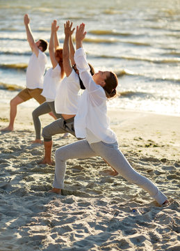 group of people making yoga exercises on beach