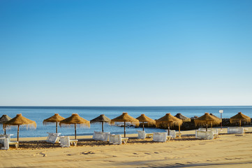 Holiday and vocation image with beach lounge and parasol on ocean sea outdoors sunny background