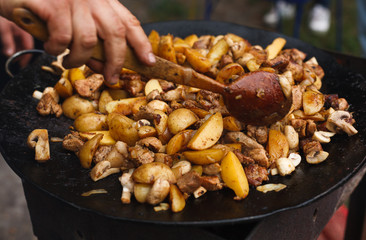 Roasted potatoes with meat cooked in metal cauldron pot
