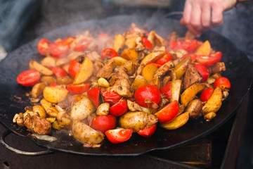 Roasted potatoes with meat cooked in metal cauldron pot