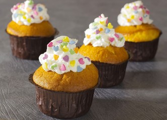 A muffins with cream and decorative colored hearts on a light background