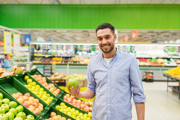 happy man buying green apples at grocery store