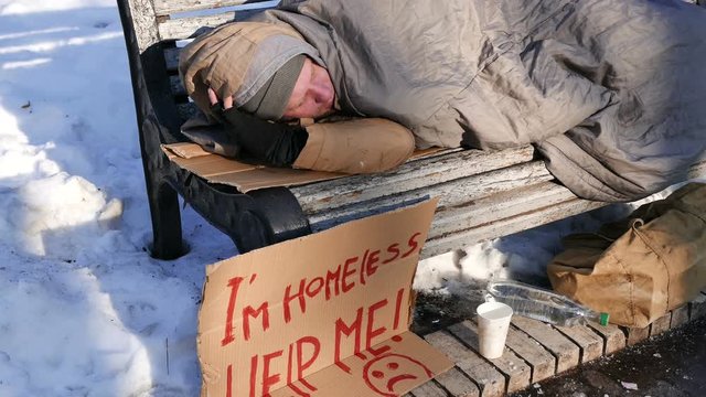
4K.Young man with cardboard in  winter city park. Homeless life close up
