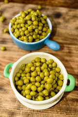 Steamed and chilled green peas ready to eat. Sweet and fresh to the taste. Here in two enameled cast iron pots on wooden cutting board.