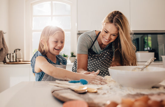 Happy young girl with her mother making dough - Powered by Adobe