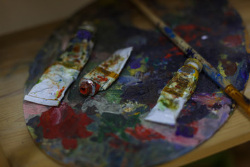 Fototapeta premium Oil paints and paint brushes on a palette close up.