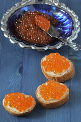 Red caviar toasts on blue background