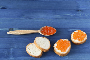Fototapeta na wymiar Red caviar toasts and wooden spoon with caviar