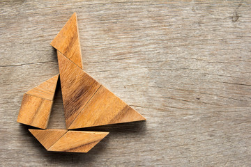 Chinese tangram puzzle in sail boat shape on wooden background