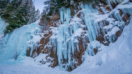Fototapeta na wymiar Frozen waterfall in a winter forest covered by snow. Franklin falls trail, Snoqualmie region, Washington state, USA
