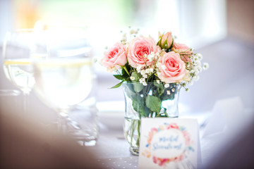 flowers of roses on wedding table with card, romantic pink background for party or event