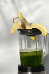 the escape, ironical picture of a human banana with sugar eyes trying to escape out of a mixer filled with a green smoothie - obrazy, fototapety, plakaty