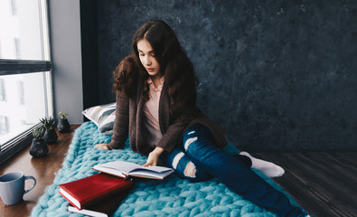 Young cheerful girl at home reading a book