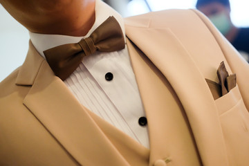Man in cream suit with brown bow tie