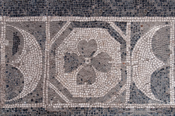 Antico pavimento in mosaico con le tessere in bianco e nero che compongono il disegno con i fiori e mezzalune