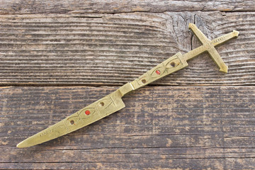 Brass letter opener knife with cross on wooden background