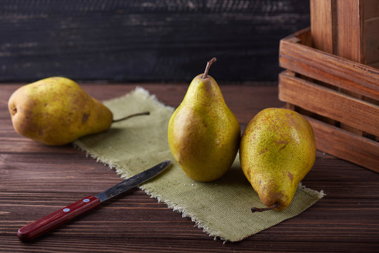 Fresh green pears and knife on a rustic background with napkin and old boxes.