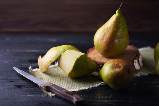Fresh green pears and knife on a rustic background on a napkin. Vertical shot