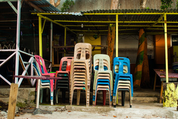 Fototapeta na wymiar Stacked colorful chairs of a closed island bar