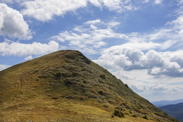 Szczyt górski na tle niebieskiego nieba z chmurami, typowa góra