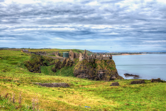 Tone mapped high definition range photo of an old castle rise on a hight cliff rock surrounded by deep water with a beautiful cloudy skyline and emerald glen.