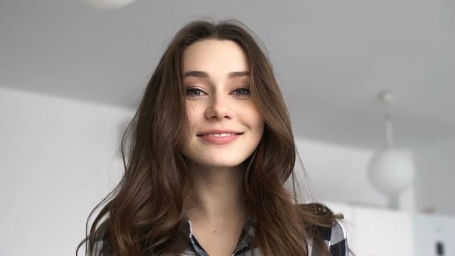 Beautiful young woman looking at camera with smile at home