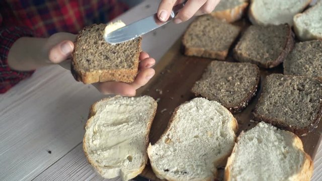 Close up of female hands spreading butter on bread in kitchen, super slow motion 240fps
