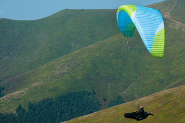 View of a paraglider above the mountain valley. Paragliding over Carpathian mountains. 