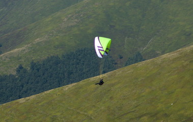 View of a paraglider above the mountain valley. Paragliding over Carpathian mountains. 