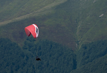 View of a paraglider above the mountain valley. Paragliding over Carpathian mountains. 