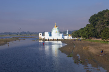 Buddhist temple at sunrise reflecting in lake and  Local Fishermen near U bein bridge at Amarapura ,Mandalay, Myanmar.