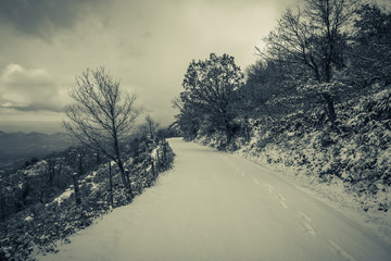 Snow covered mountain road with footsteps and sea view beyond