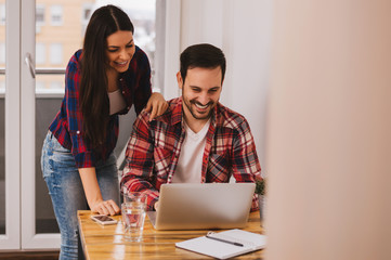 Beautiful couple of designers in casual clothes is using laptop