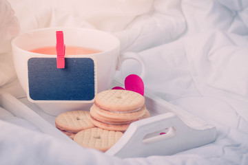 Breakfast in bed in Valentines day. Cup of tea and cookies. Black board for Message,copy space .