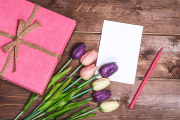 Romantic and pink Valentine's day decoration with present and DIY love card. Beautiful bouquet of purple tulips and card on wooden background. Mothers day card .On March 8 is Women's Day
