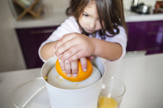 Little girl making orange juice