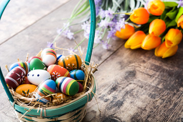 Colored easter eggs in a basket on wooden table
