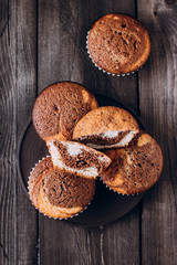 Homemade sweet chocolate vanilla muffins from two types of dough on wooden table background. Top view with copy space
