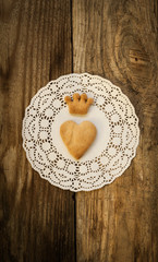 Fototapeta na wymiar cookies in the shape of a heart and cookies in the shape of a crown on a white napkin on a wooden table