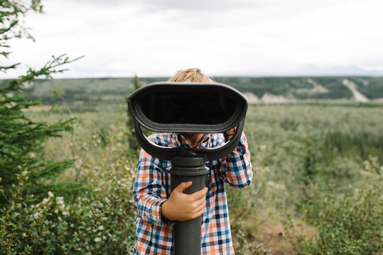 Boy looking at landscape through viewing scope 