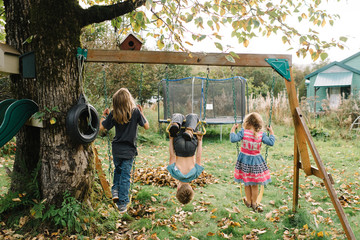 Siblings playing on swings in garden 