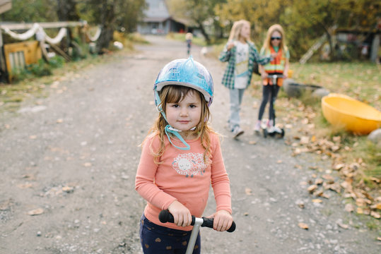 Female child and scooter with protective headwear