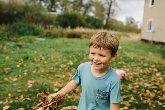 Young boy holding autumn leaves 
