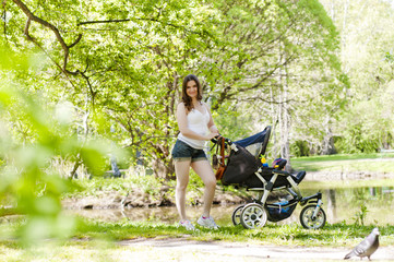 Young woman with a stroller in the summer park